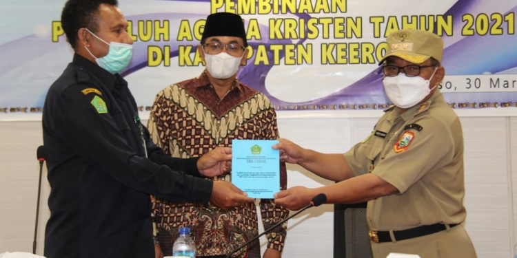 Caption : Kepala Kanwil Kemenag Provinsi Papua, Pendeta Amsal Yowei ketika memberikan plakat kepada Wakil Bupati Keerom, Drs. Wahfir Kosasih, SH, MH, MSi, saat kegiatan Pembinaan Penyuluh Agama Kristen di Kabupaten Keerom,Selasa (30/3)